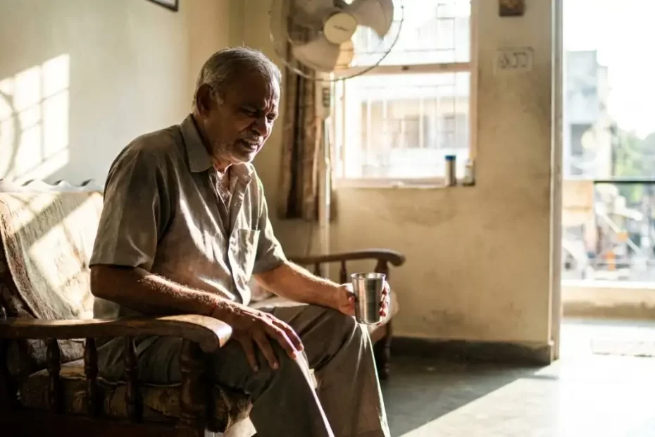 Elderly Indian man experiencing sudden dehydration joint pain during the Ahilyanagar summer heatwave.